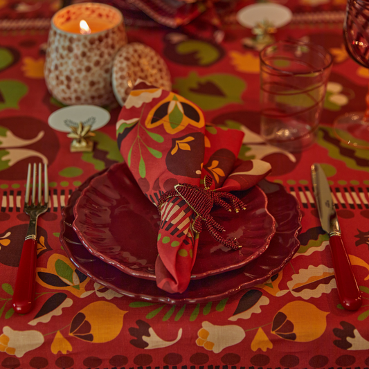 Festive set table with red tablecloth, napkins and plates
